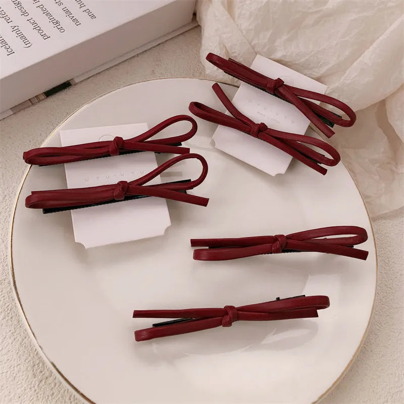 Wine red genuine leather bow hair barrette with metal clip on a white background.