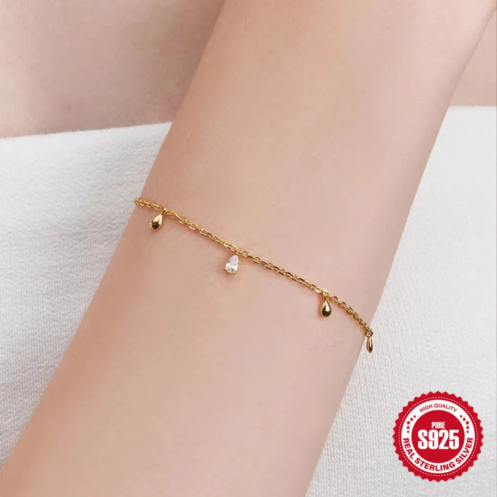 S925 sterling silver bracelet with gold tone water drop diamond pendant on a wrist.