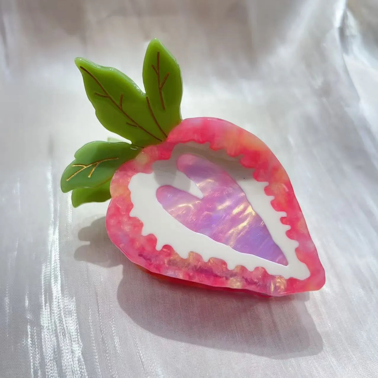 Close-up of a handmade strawberry hairpin in red on a pink background.