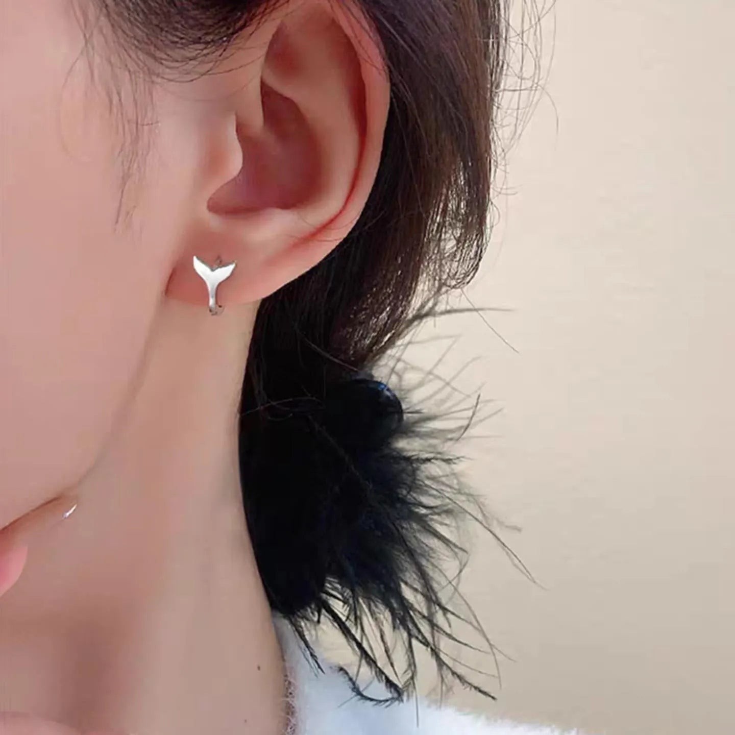 A pair of simple women's fishtail earrings in a gold tone finish on a copper base.