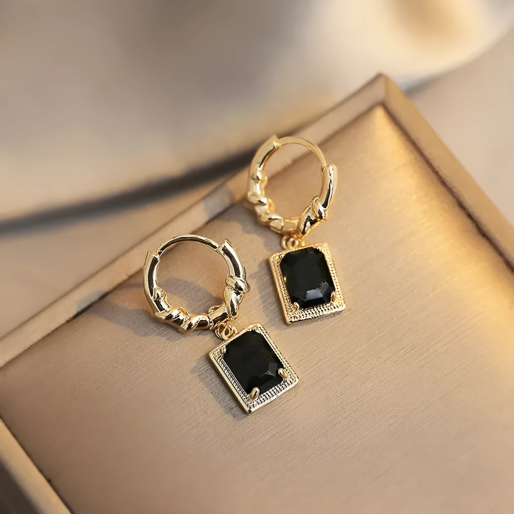 Close-up of women's geometric quadrilateral copper earrings with a black zircon stone and butterfly back.