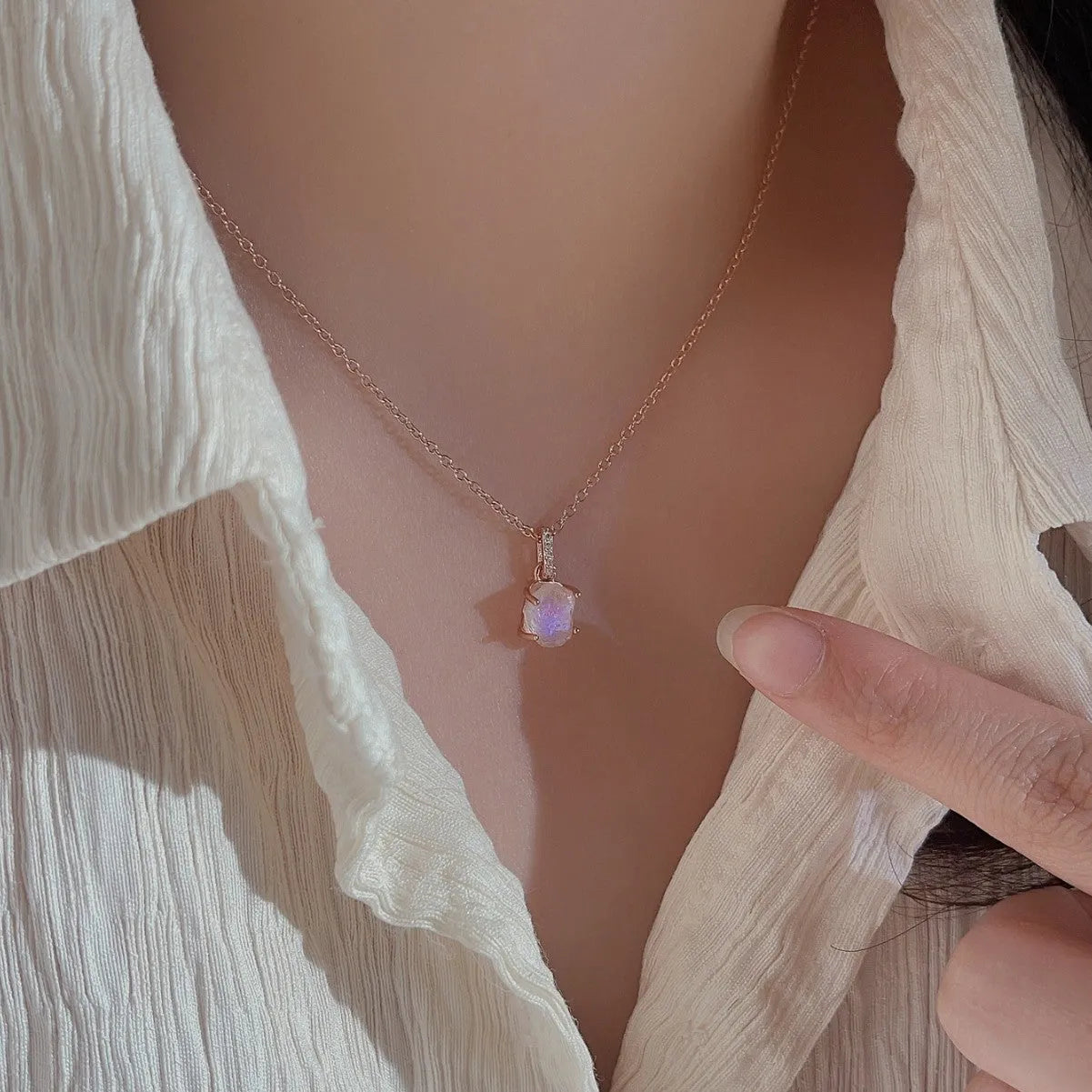 Close-up of a sterling silver necklace with a square moonstone pendant on an adjustable curb chain.