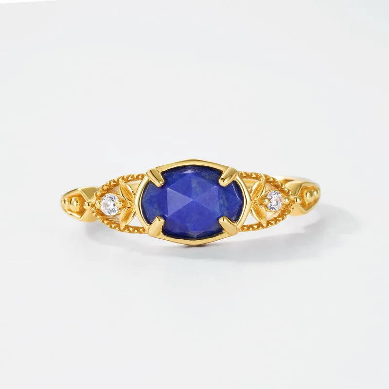 A silver geometric ring with a natural blue lapis lazuli stone, showing ellipse shape and round details.