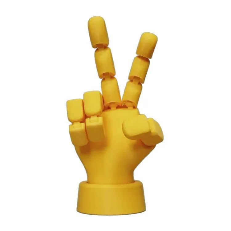 Yellow articulated hand prop ornament with movable joints on a desk, showing poseable fingers and measuring 5cm wide.