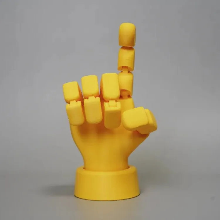 Yellow articulated hand prop ornament with movable joints on a desk, showing poseable fingers and measuring 5cm wide.