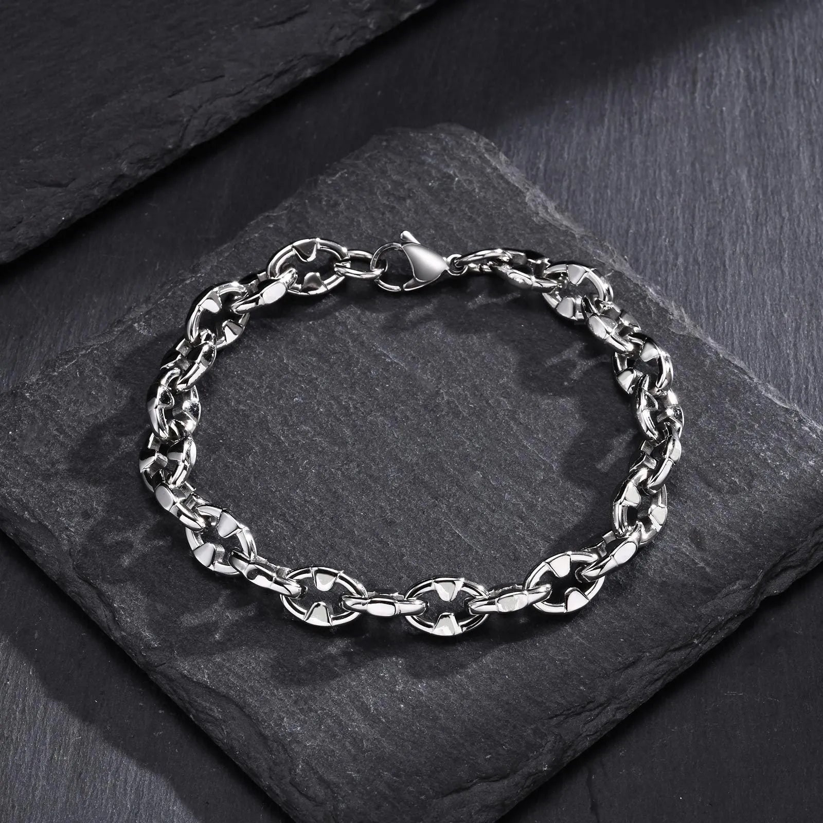 Close-up of a thick geometric chain bracelet made from polished stainless steel, on a wrist.