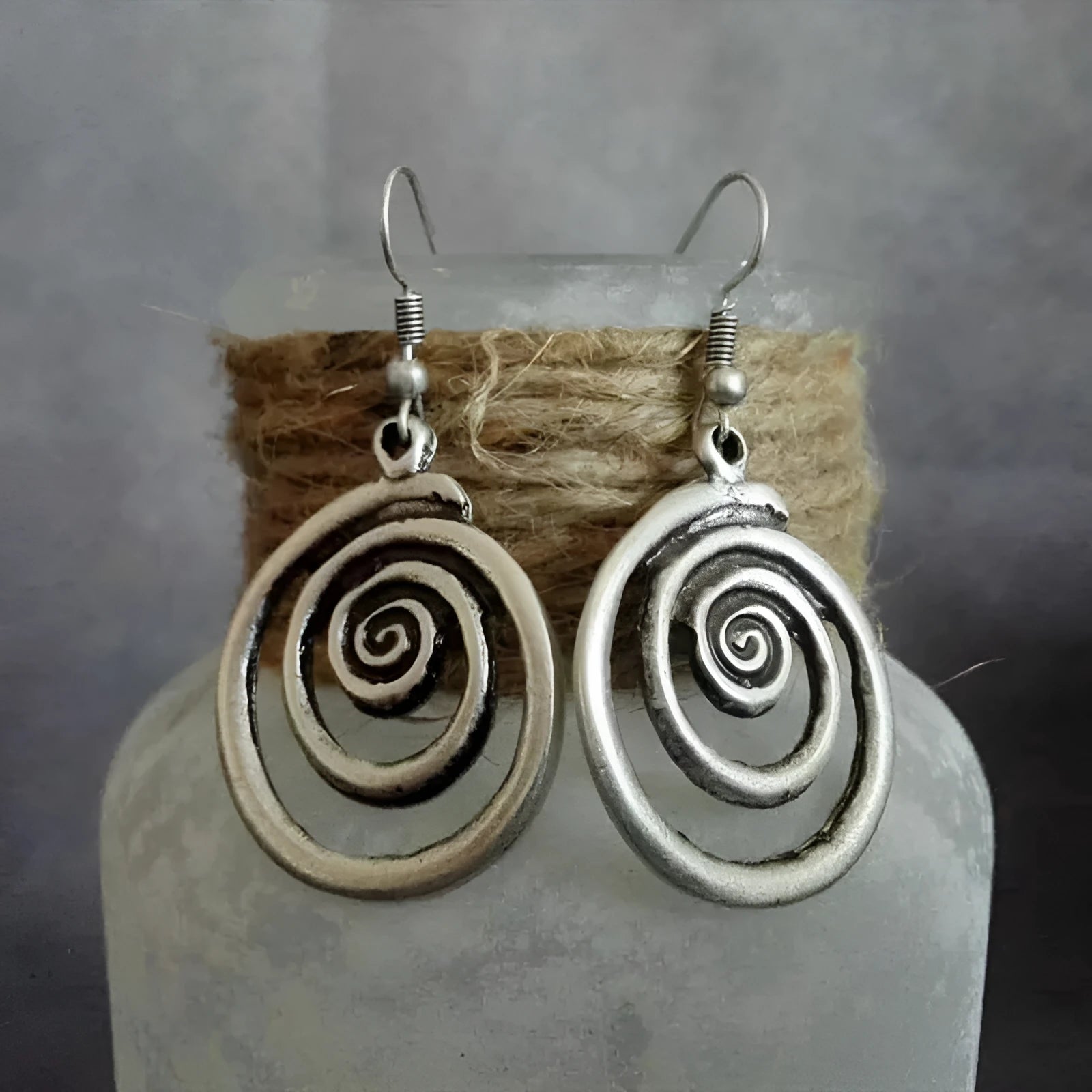 Pair of silver geometric spiral earrings with a distressed finish on a white background.