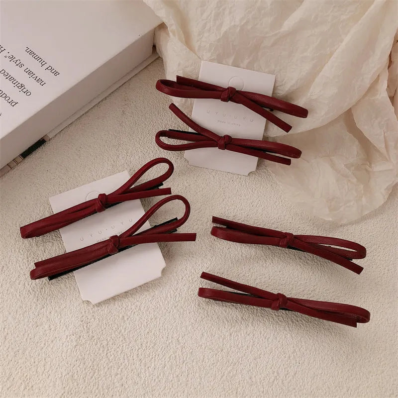 Wine red genuine leather bow hair barrette with metal clip on a white background.
