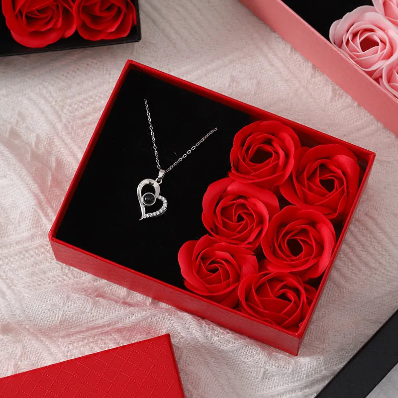 Red Valentine's gift box open to show six pink soap roses with a matching handbag beside it