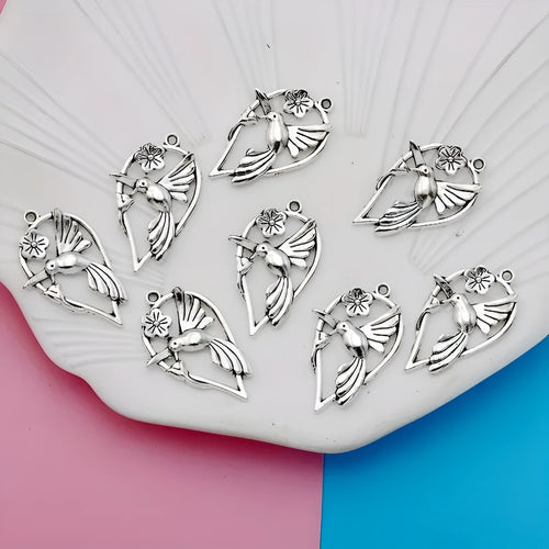 Close-up of a silver-tone alloy magpie charm pendant with engraved feather details on wings and tail for DIY jewellery.