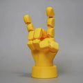 Yellow articulated hand prop ornament with movable joints on a desk, showing poseable fingers and measuring 5cm wide.