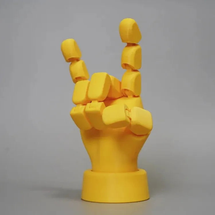 Yellow articulated hand prop ornament with movable joints on a desk, showing poseable fingers and measuring 5cm wide.