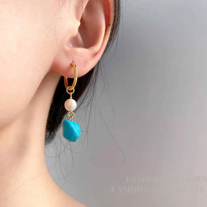 A pair of geometric clip-on earrings made of copper with turquoise and cultured pearls.