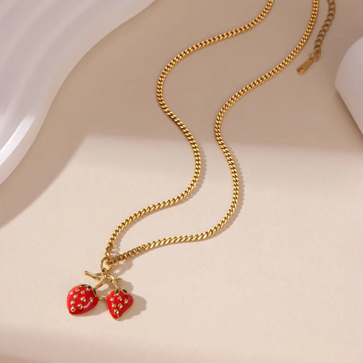 Close-up of a red strawberry pendant necklace on a silver alloy chain with adjustable clasp.