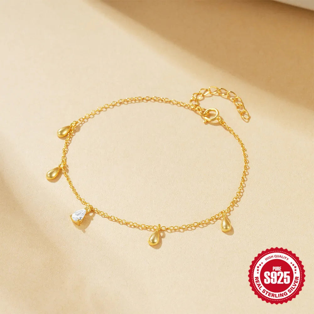S925 sterling silver bracelet with gold tone water drop diamond pendant on a wrist.