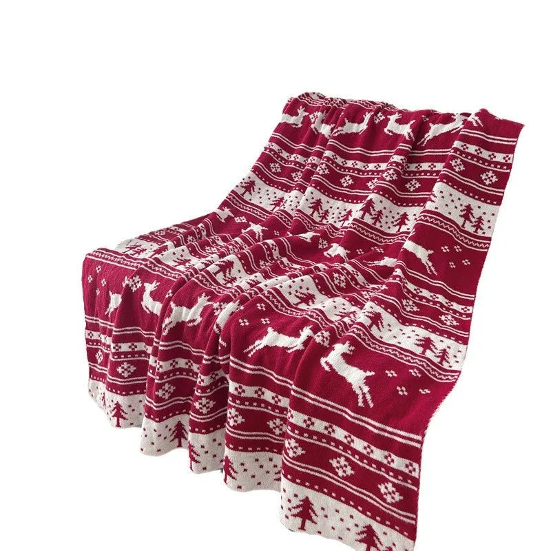 Red and white Christmas blanket with cartoon reindeer pattern on a sofa