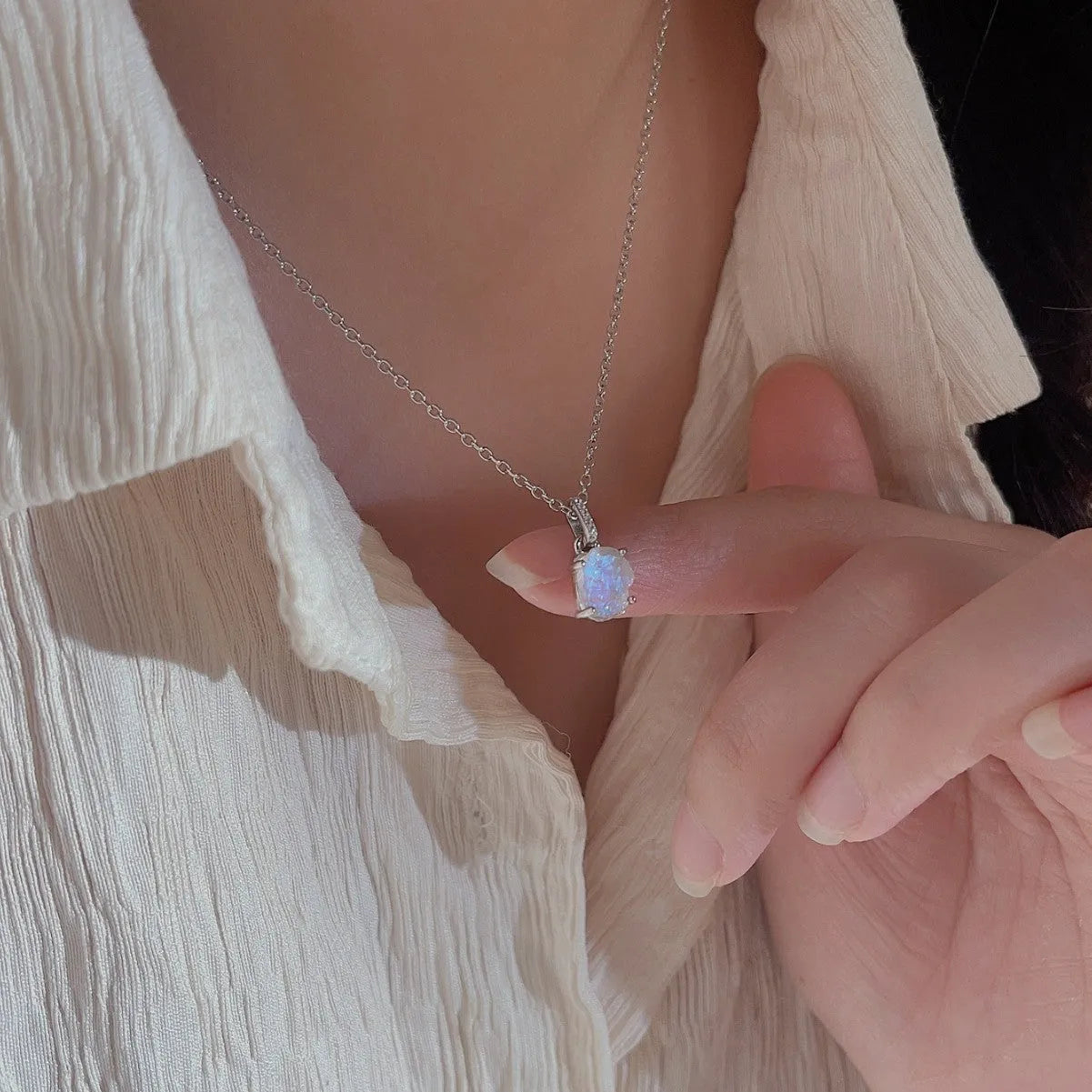 Close-up of a sterling silver necklace with a square moonstone pendant on an adjustable curb chain.