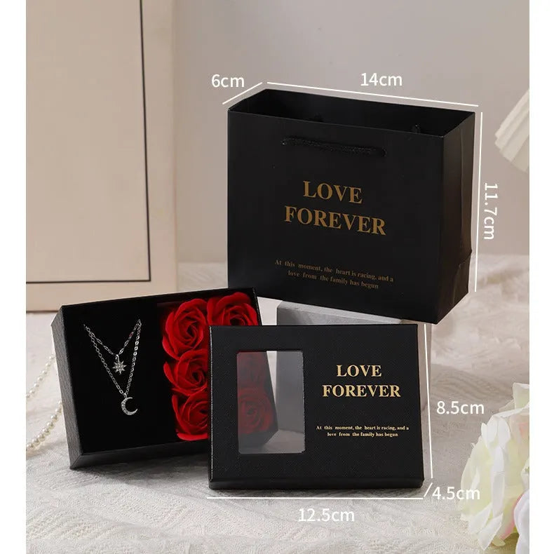 Red Valentine's gift box open to show six pink soap roses with a matching handbag beside it