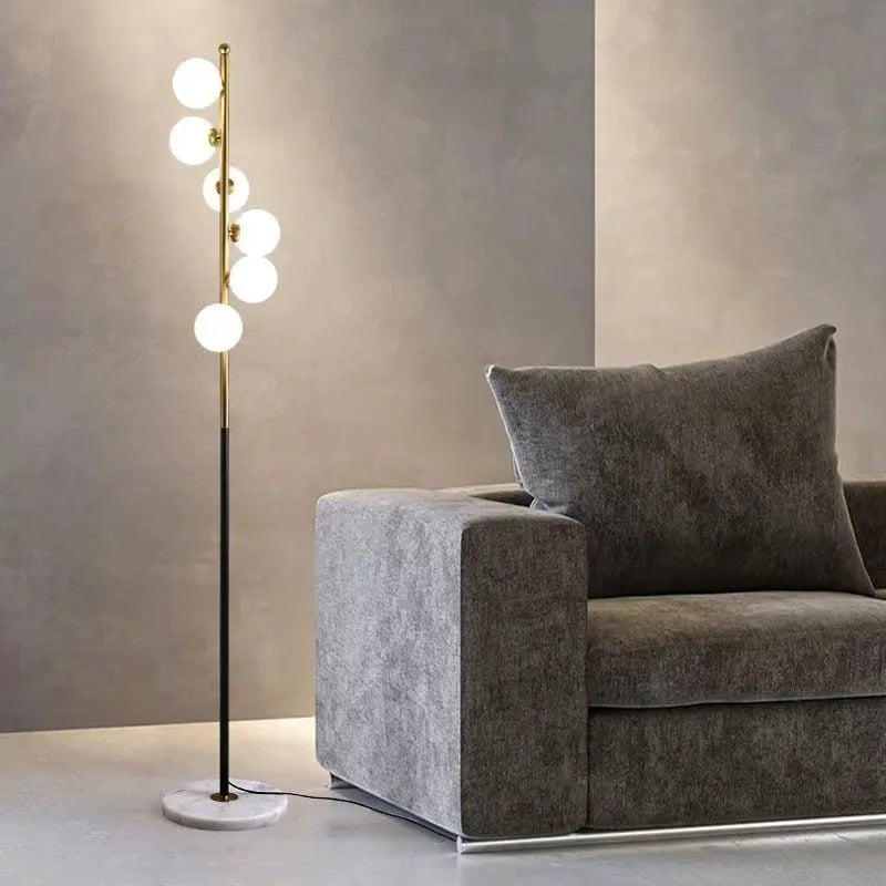 Tall minimalist Nordic floor lamp with wrought iron frame, glass shade, and circular marble base.