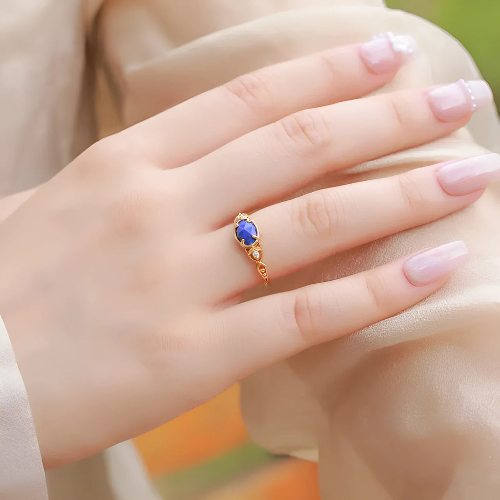 A silver geometric ring with a natural blue lapis lazuli stone, showing ellipse shape and round details.