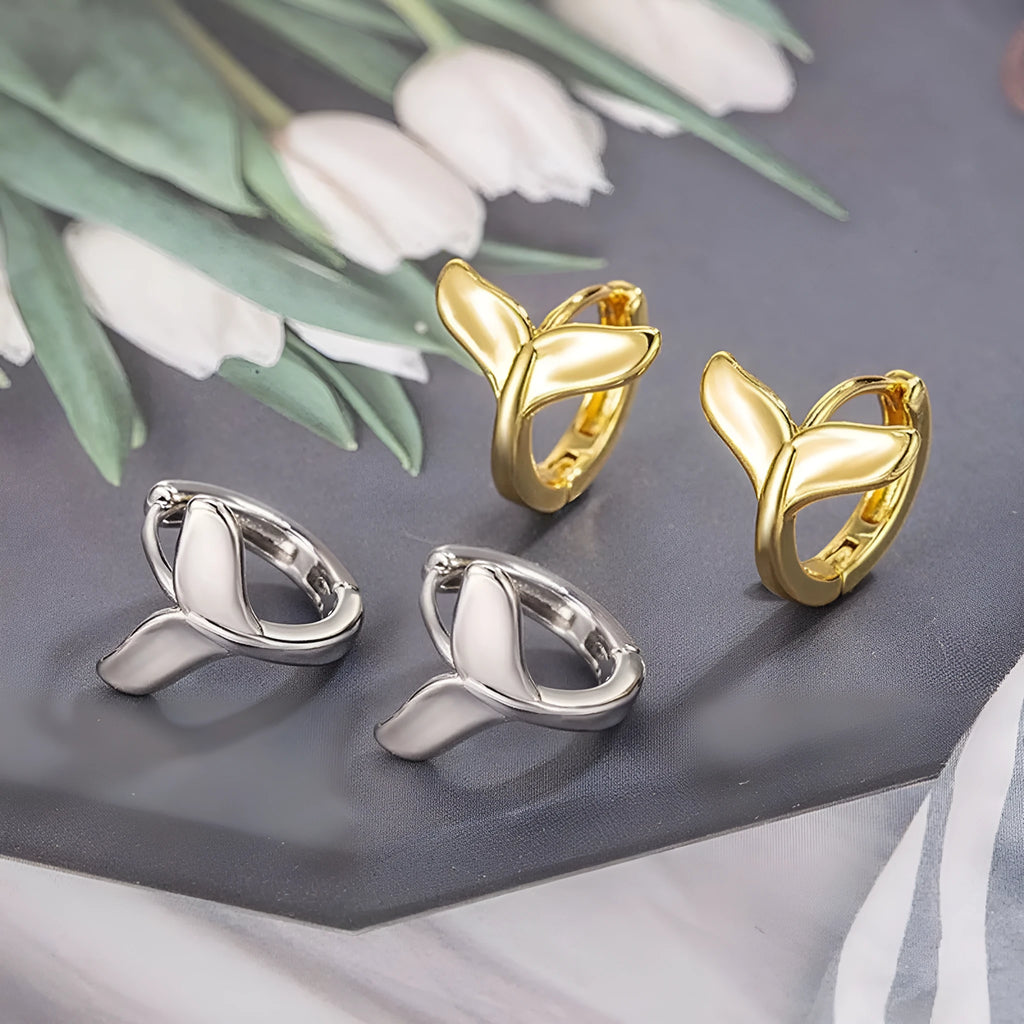 A pair of simple women's fishtail earrings in a gold tone finish on a copper base.