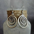 Pair of silver geometric spiral earrings with a distressed finish on a white background.