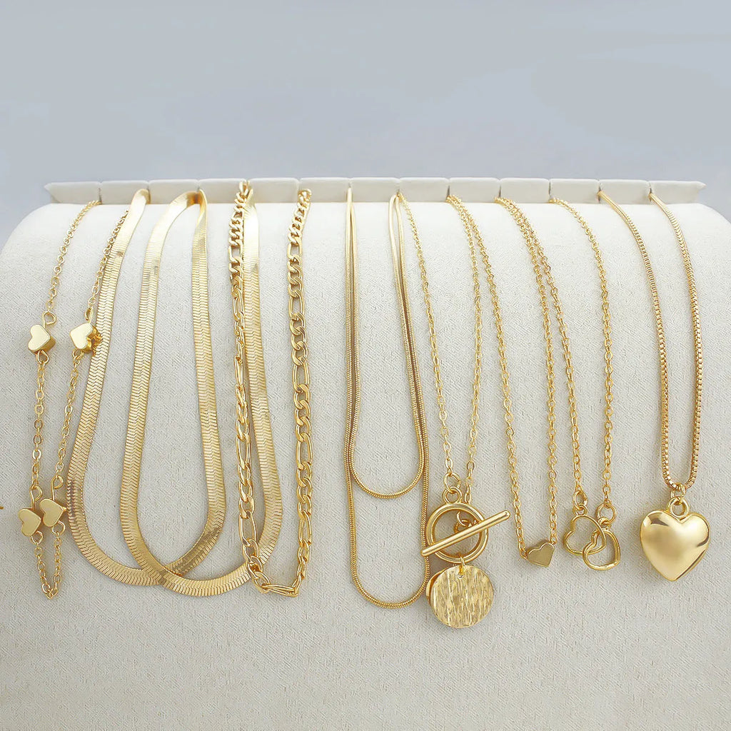 Set of ten gold women's fashion necklaces with snake bone chains and adjustable length on a white background.