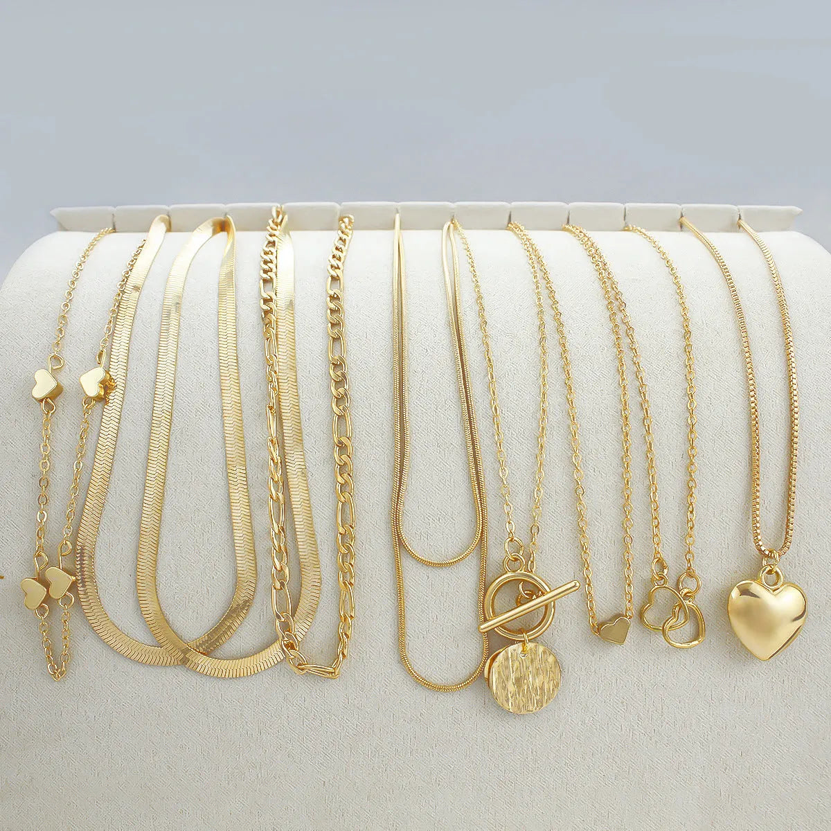 Set of ten gold women's fashion necklaces with snake bone chains and adjustable length on a white background.