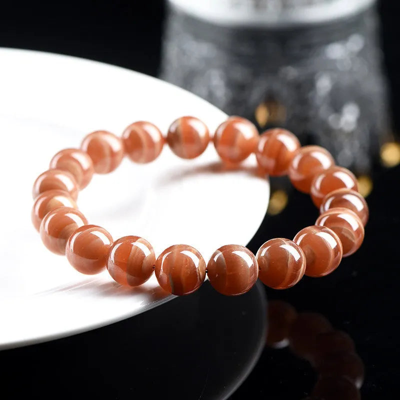 Natural Old Mine Rhodochrosite mineral bracelet with round beads in 6mm or 8mm size on a wrist.