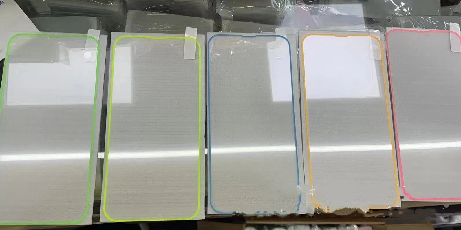 Fluorescent blue tempered glass screen protector glowing on an iPhone 13 in a dark setting.
