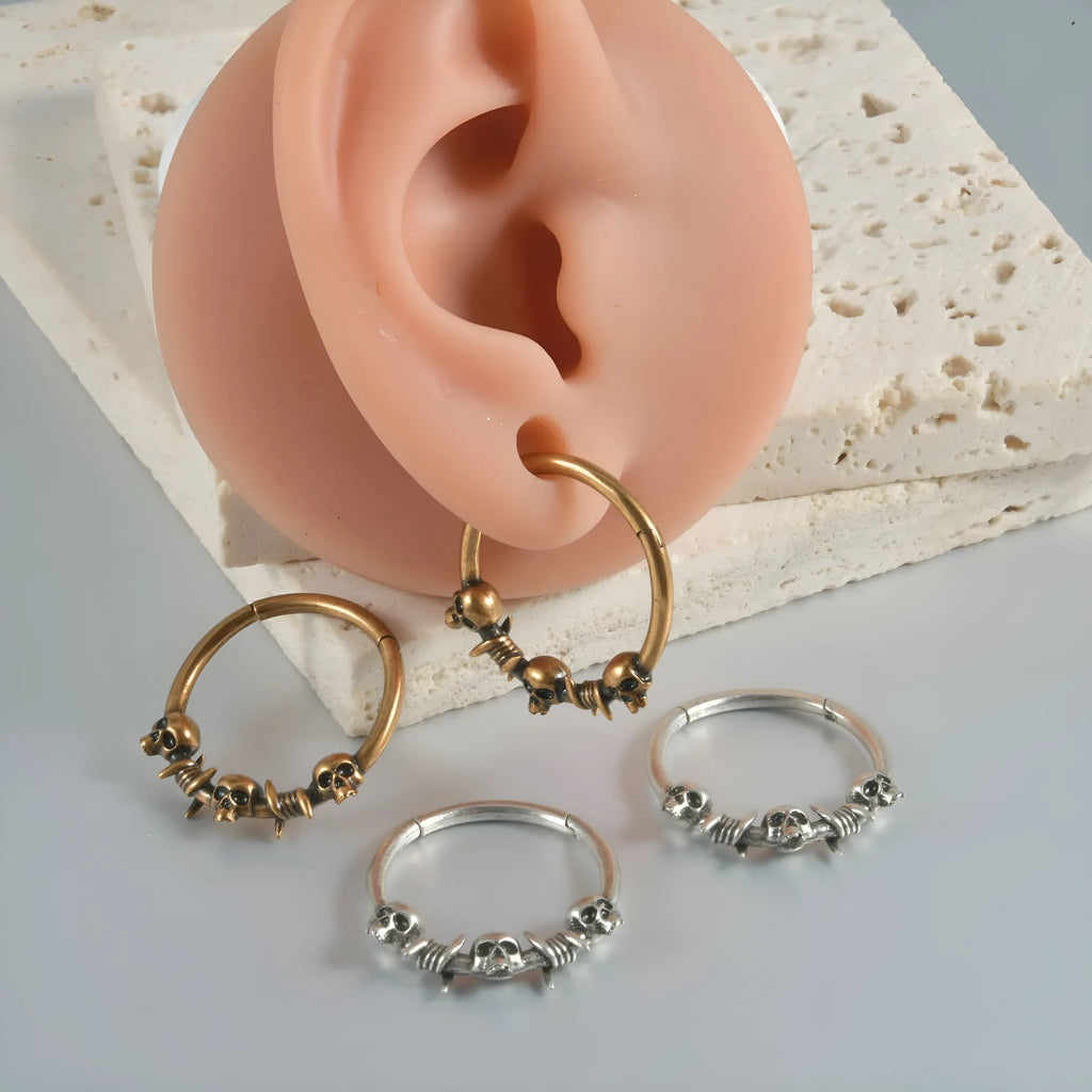 A pair of vintage-style copper earrings with an embossed ghost head design on a stud post, showing an antique silver finish.