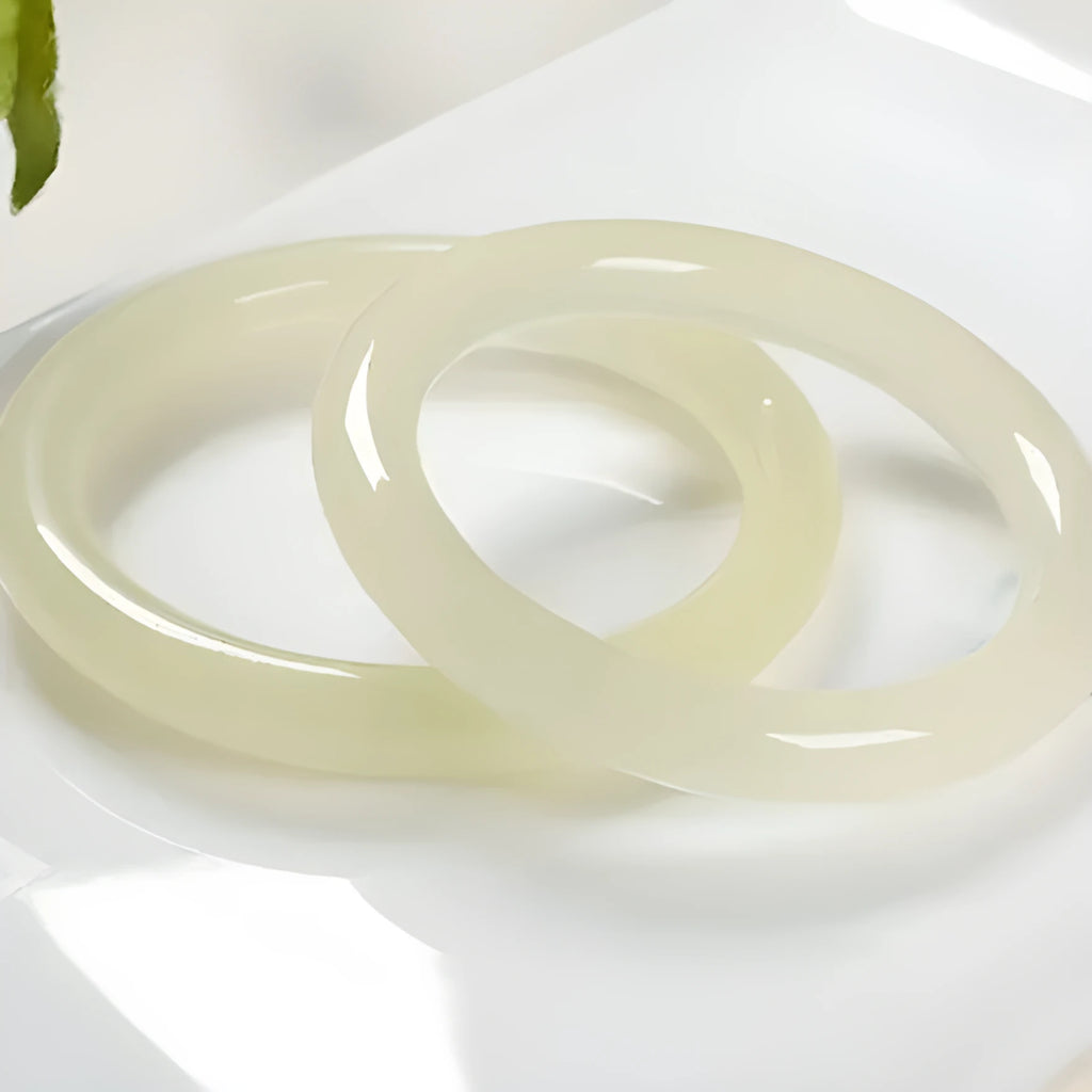 A polished natural jade round bar bracelet showing a winding silk texture on its surface.