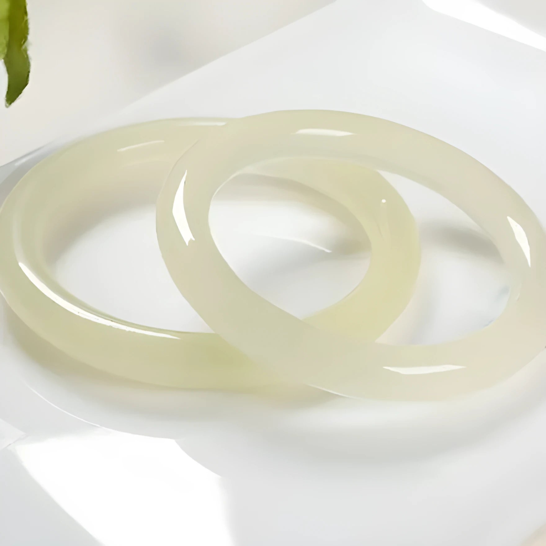 A polished natural jade round bar bracelet showing a winding silk texture on its surface.