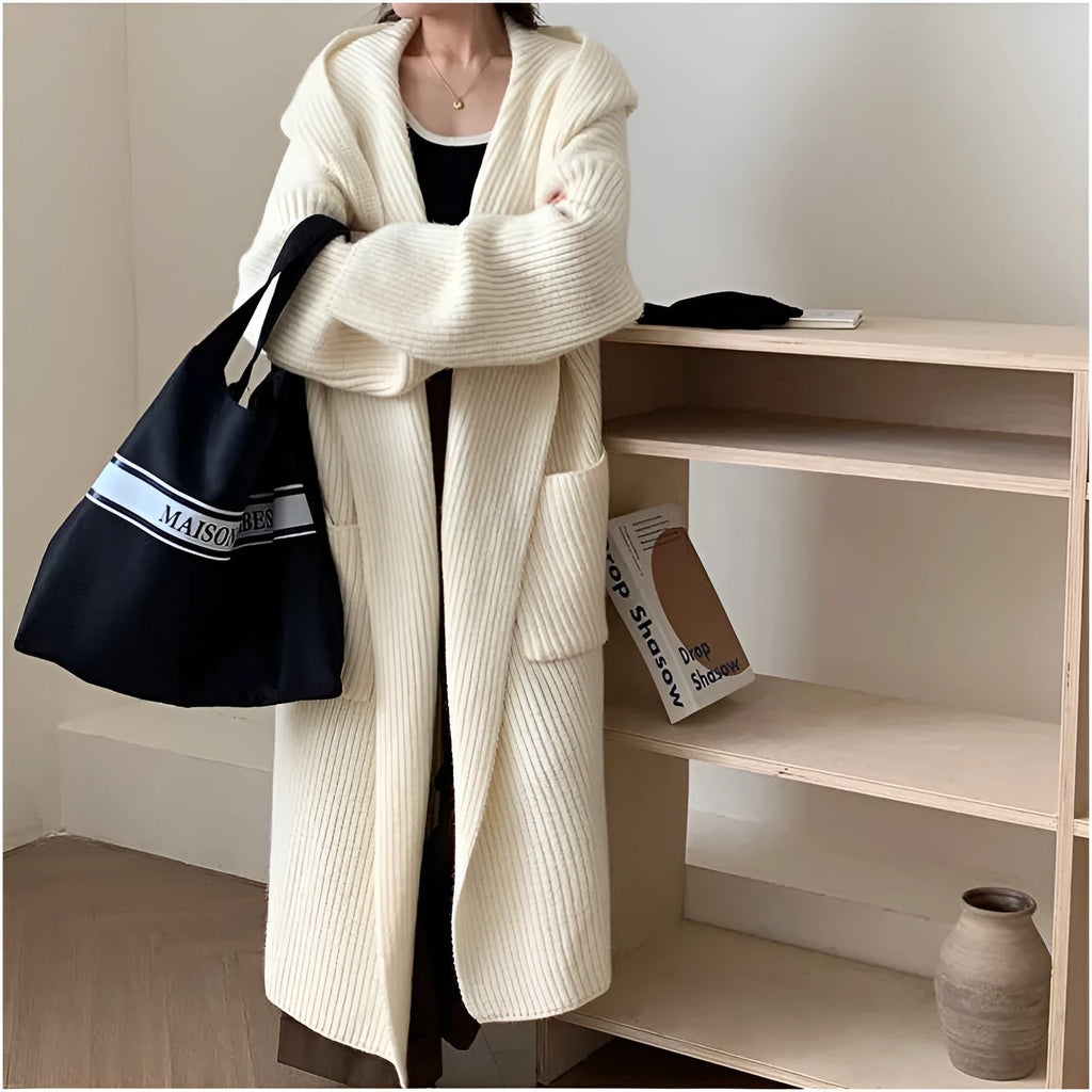 Woman wearing a longline loose grey hooded cardigan coat with raglan sleeves.