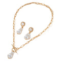 Gold-toned baroque pearl pendant necklace and matching stud earrings set on a dark background.