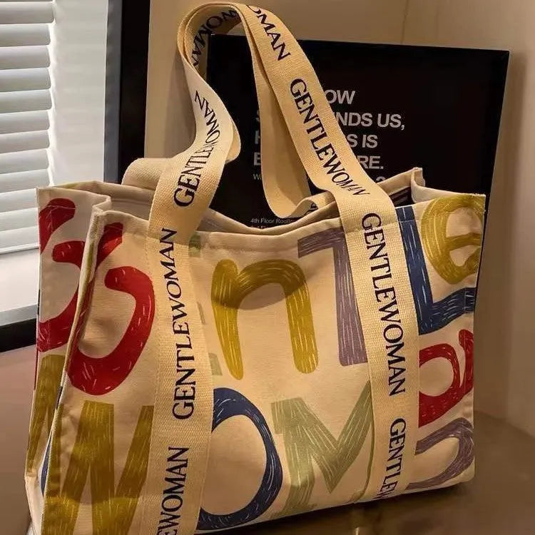 Large canvas women's tote bag with printed design, shown in shopping and travel use contexts.