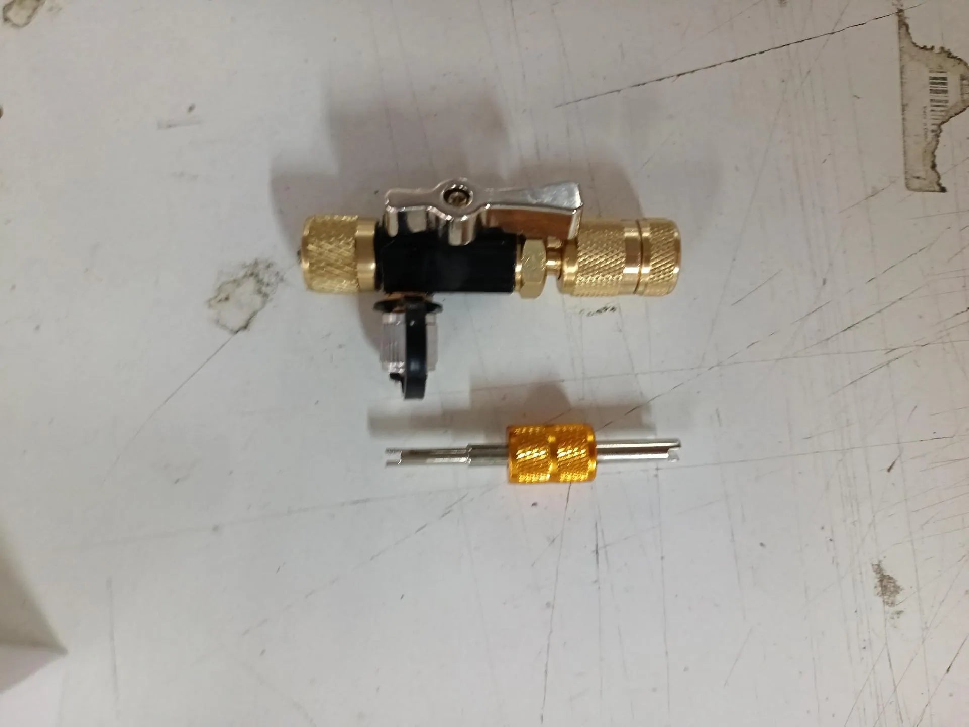 Metal valve core disassembly tool set showing valve remover and wrench on a workbench.