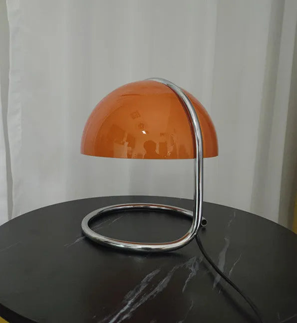 Retro metal mushroom table lamp with three-colour light in orange finish on a bedside table