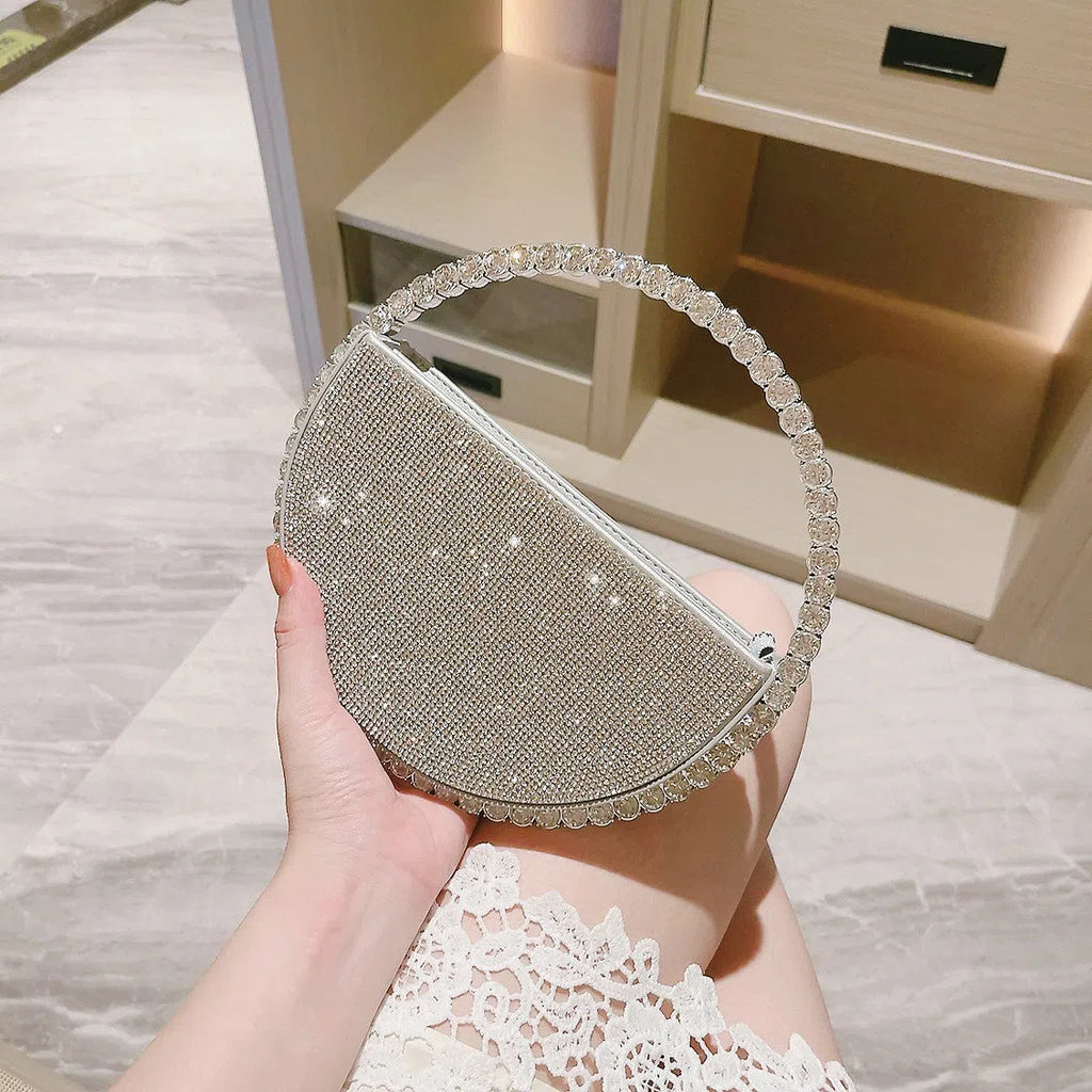 Round silver white PU evening bag with rhinestone details and crossbody strap on flat surface
