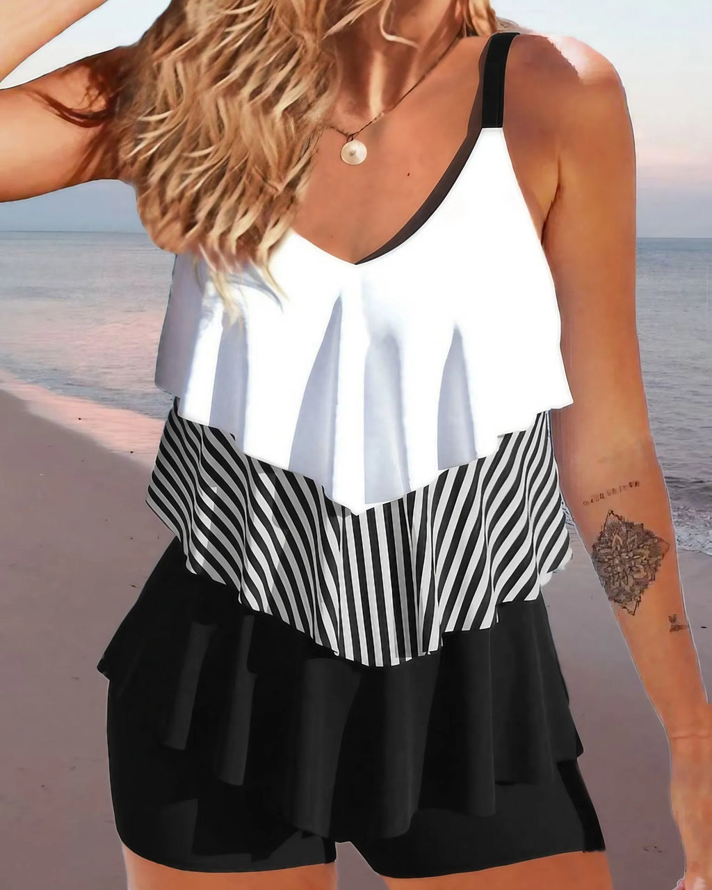 Women's sleeveless backless bikini swimsuit with spaghetti straps and ruffle detail on a solid colour background.