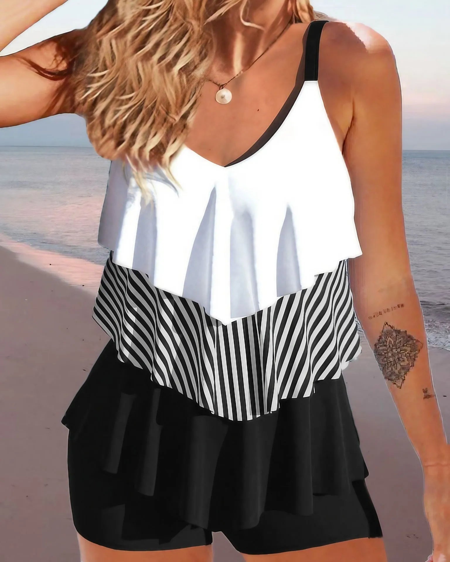 Women's sleeveless backless bikini swimsuit with spaghetti straps and ruffle detail on a solid colour background.