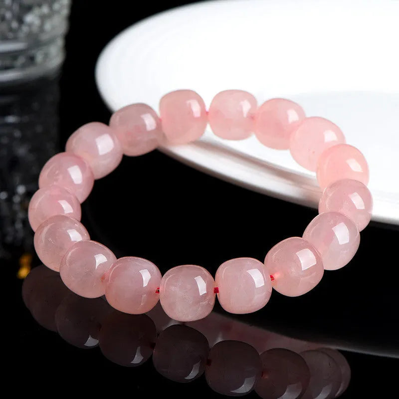 Pink natural crystal bracelet with barrel-shaped beads on a wrist.