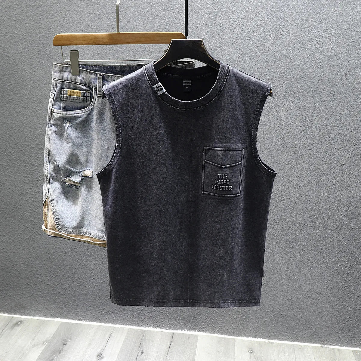 Men's loose fit black cotton sleeveless t-shirt on a hanger, showing straight hem design.