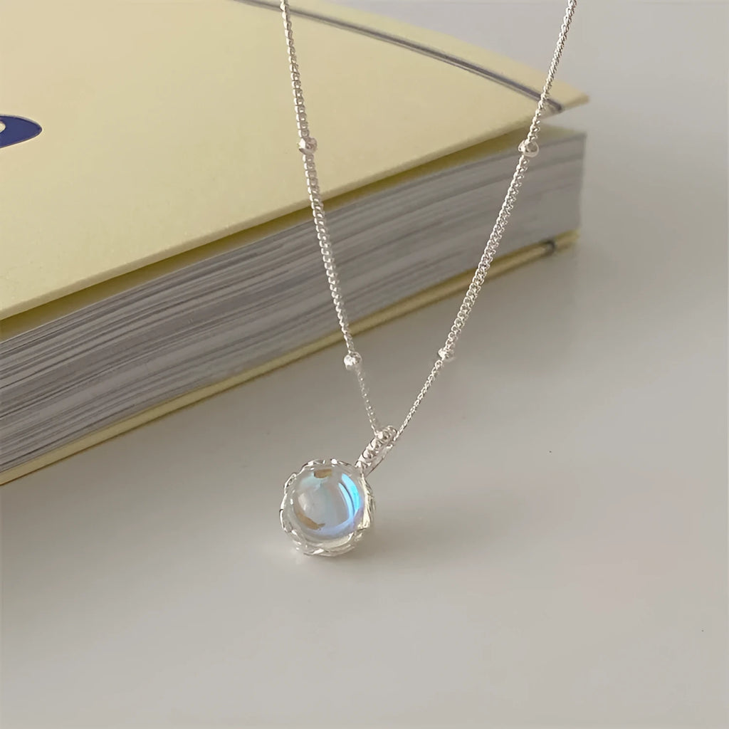 Silver geometric round stone pendant on a women's curb chain necklace.