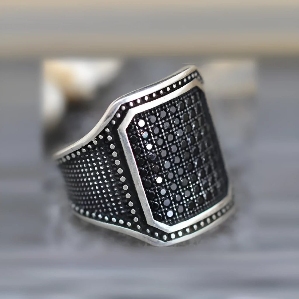 Black alloy fashion ring with a central zircon stone and copper metal inlays on a dark band.