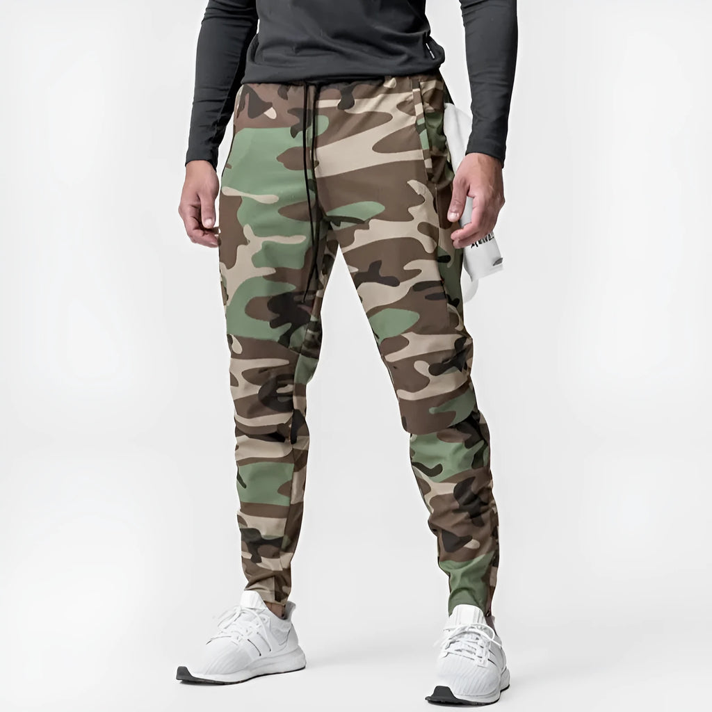 Man wearing dark grey loose-fit fitness trousers with tied ankle cuffs, made from quick-dry polyester fabric.