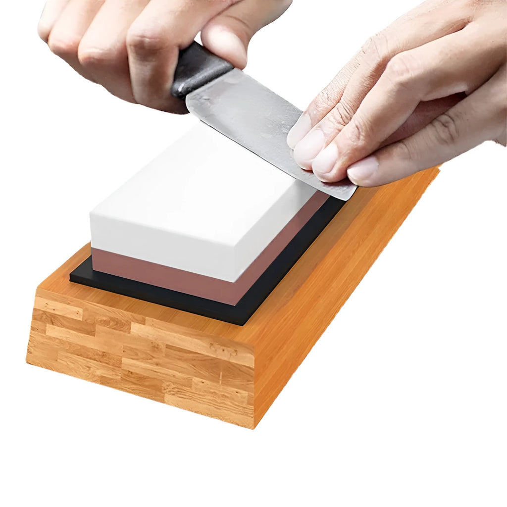 Red and white dual-grit kitchen whetstone on a bamboo base with sharpening accessories.