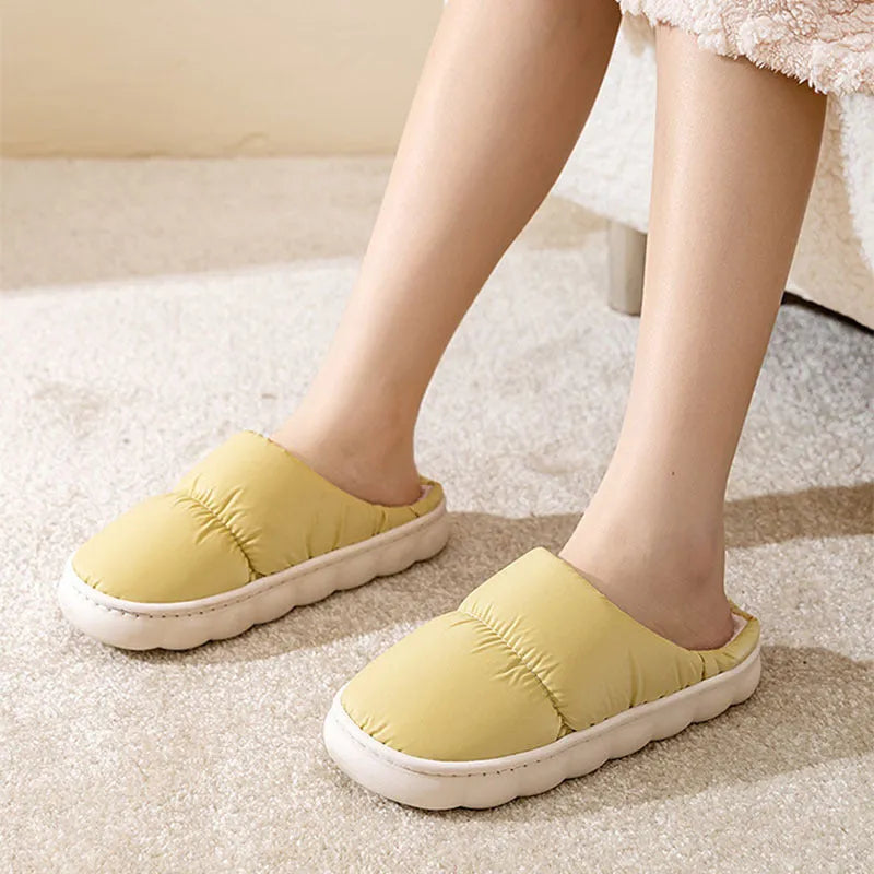 A pair of thick-soled house slippers with an artificial leather upper and plush lining, shown in a selection of colours.