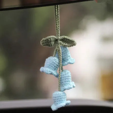 Green and white crocheted wool car plant decoration with a white hanging rope.