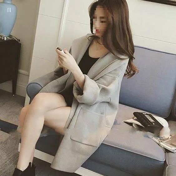 Plus size woman wearing a thin, loose-fit grey coat with lace detail and long sleeves.